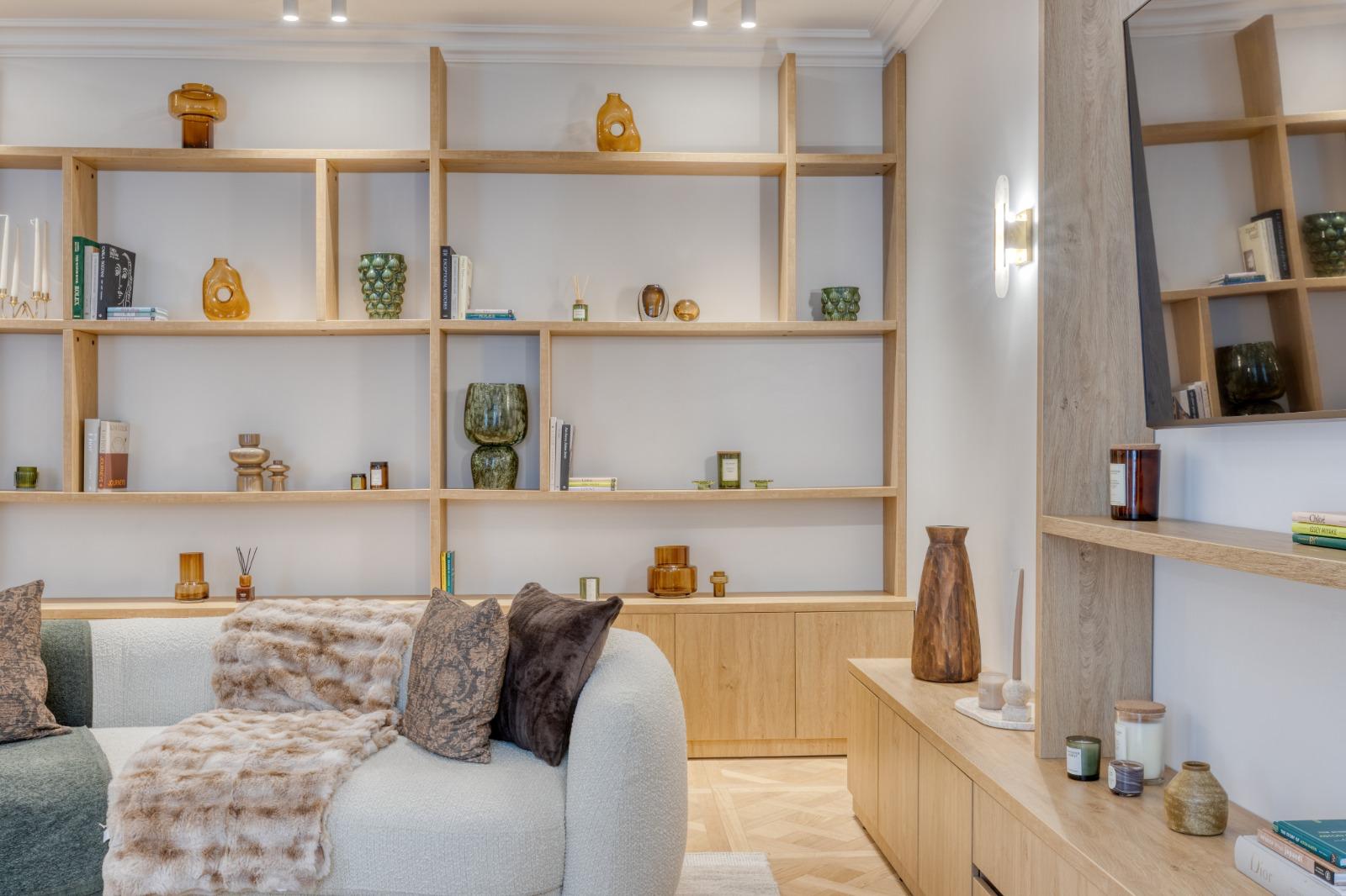 Bibliothèque sur mesure en chêne clair et meuble bas assorti dans le salon d'un appartement rénové